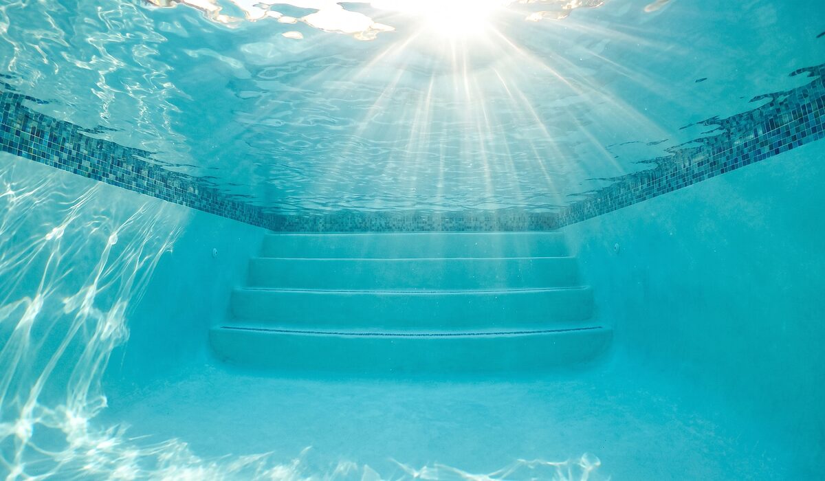 Underwater view of a clear swimming pool with sunlight through the water