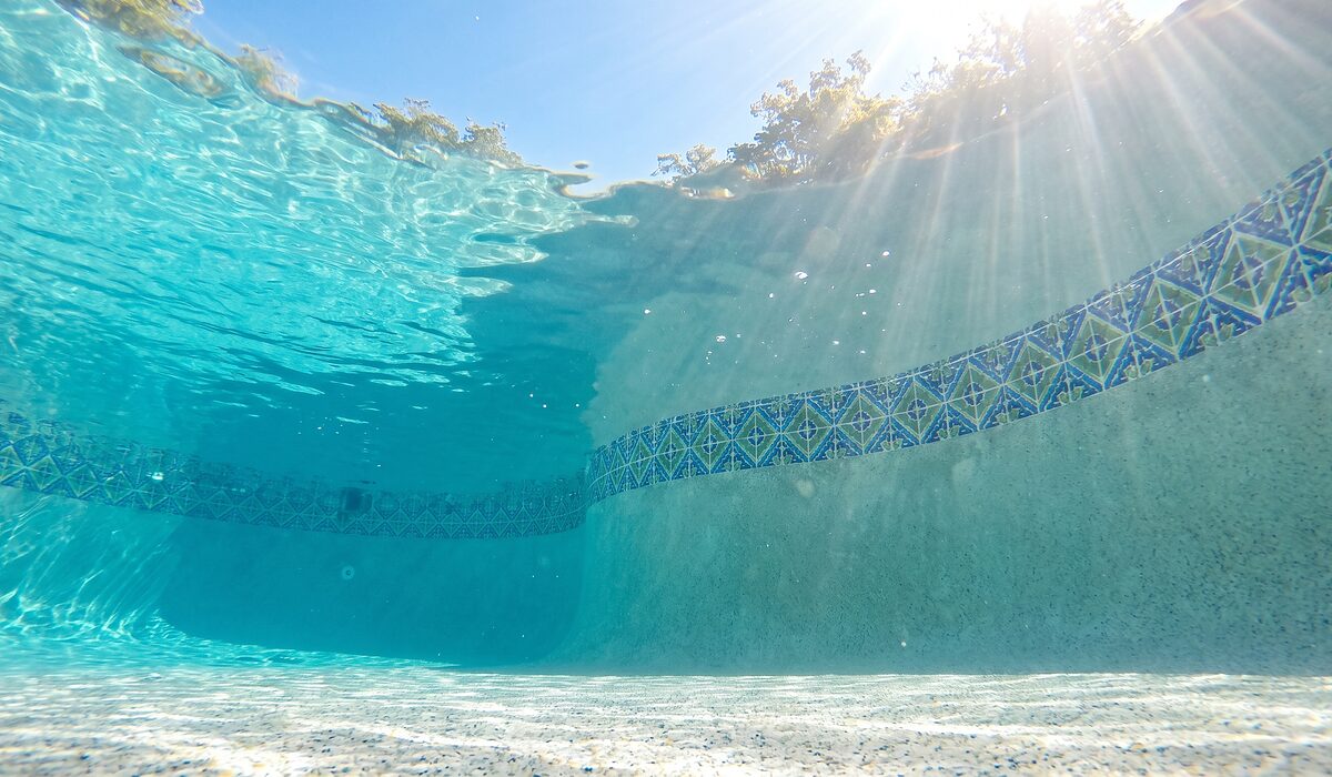 Underwater view of a clear swimming pool with sunlight through the water