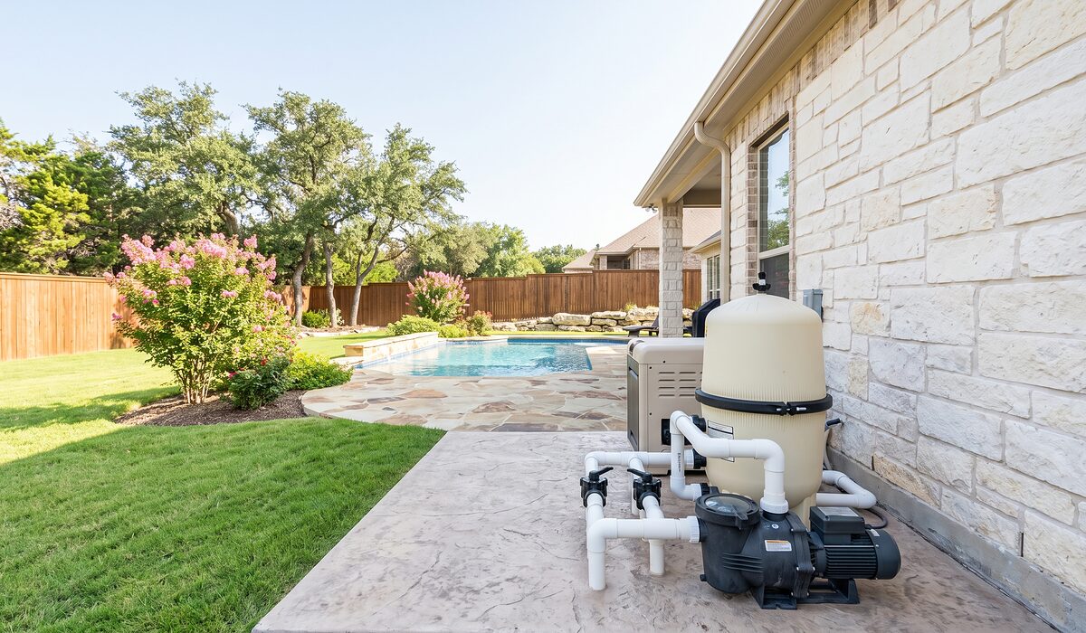 Pool equipment pad with pump, filter, and plumbing beside a Texas home