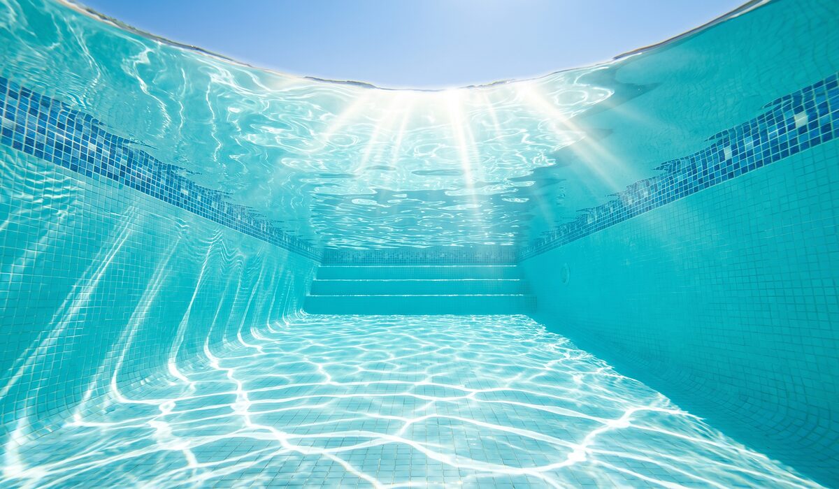 Underwater view of a clear swimming pool with sunlight through the water