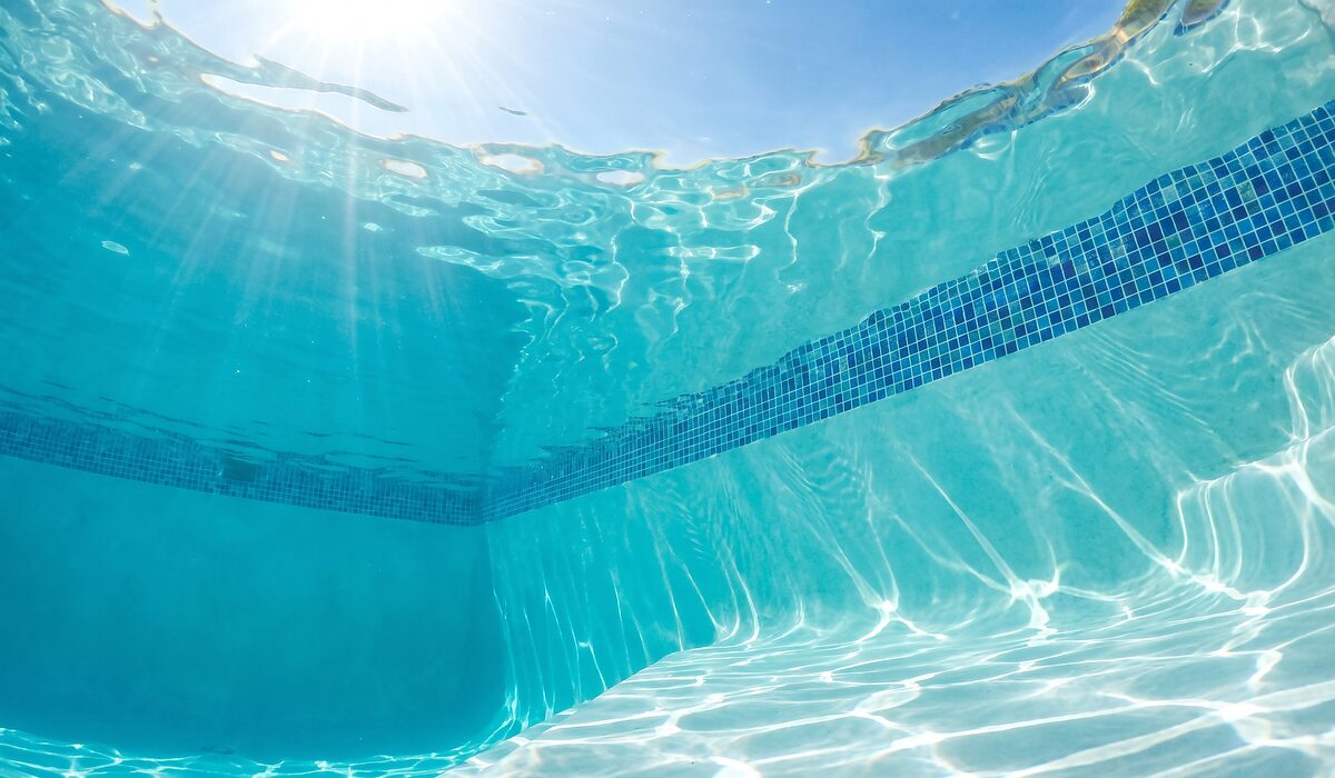 Underwater view of a clear swimming pool with sunlight through the water