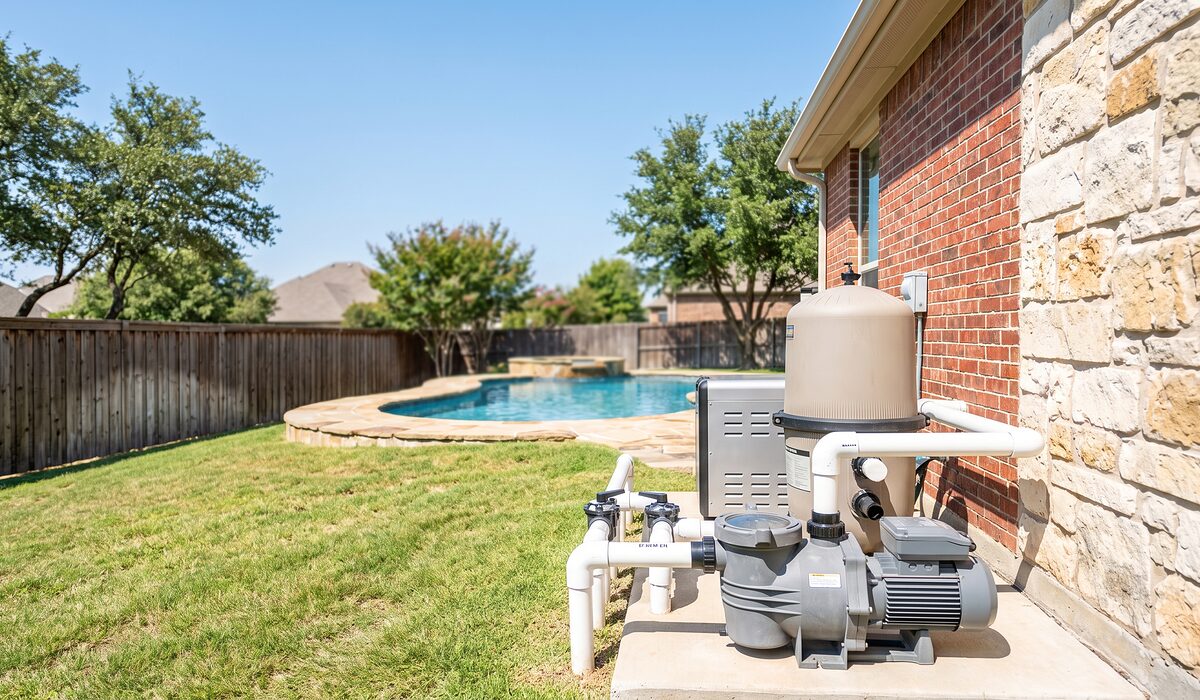 Pool equipment pad with pump, filter, and plumbing beside a Texas home