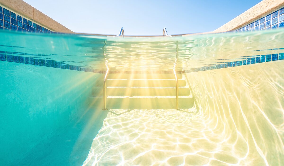 Underwater view of a clear swimming pool with sunlight through the water