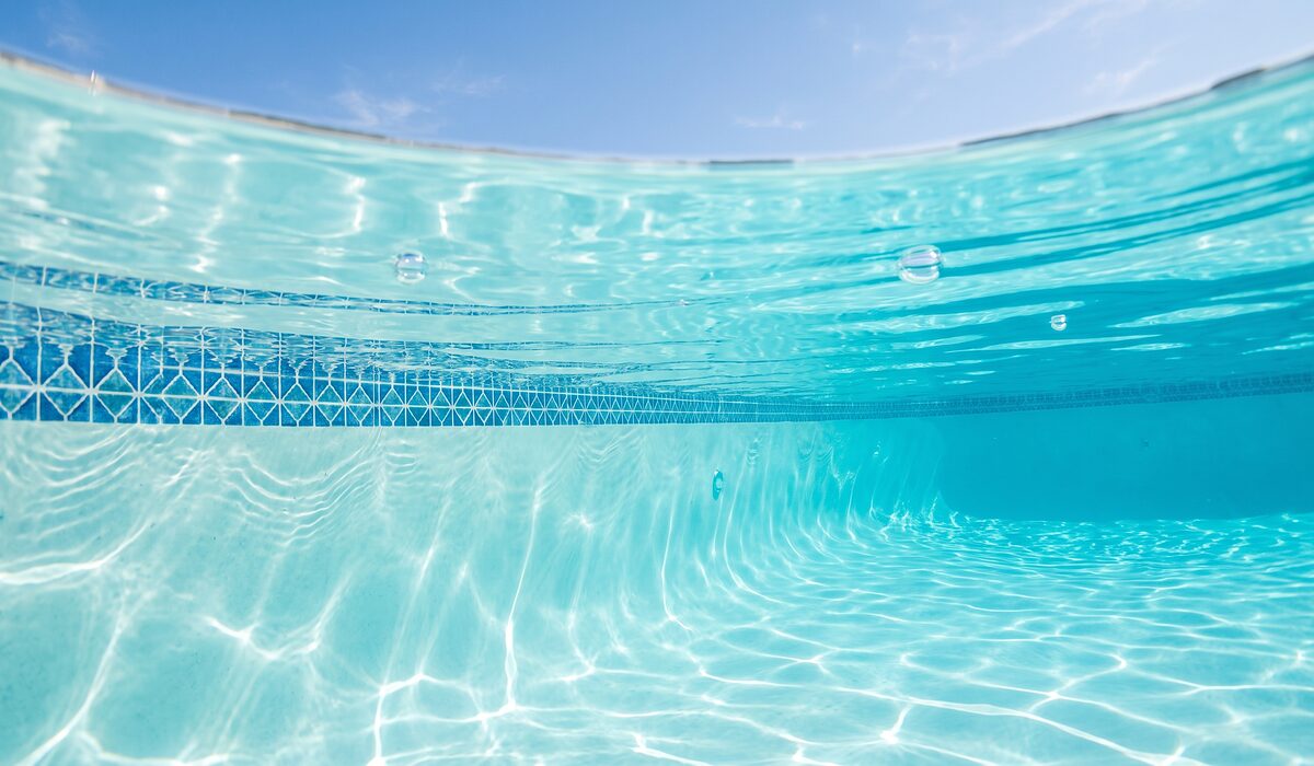Underwater view of a clear swimming pool with sunlight through the water