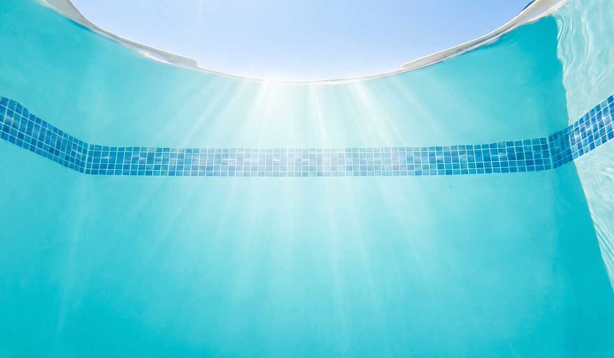 Underwater view of a clear swimming pool with sunlight through the water