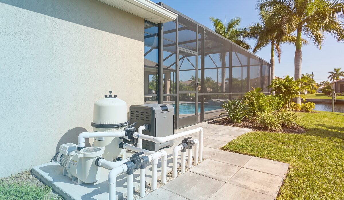 Pool equipment pad with pump, filter, and plumbing beside a Florida home