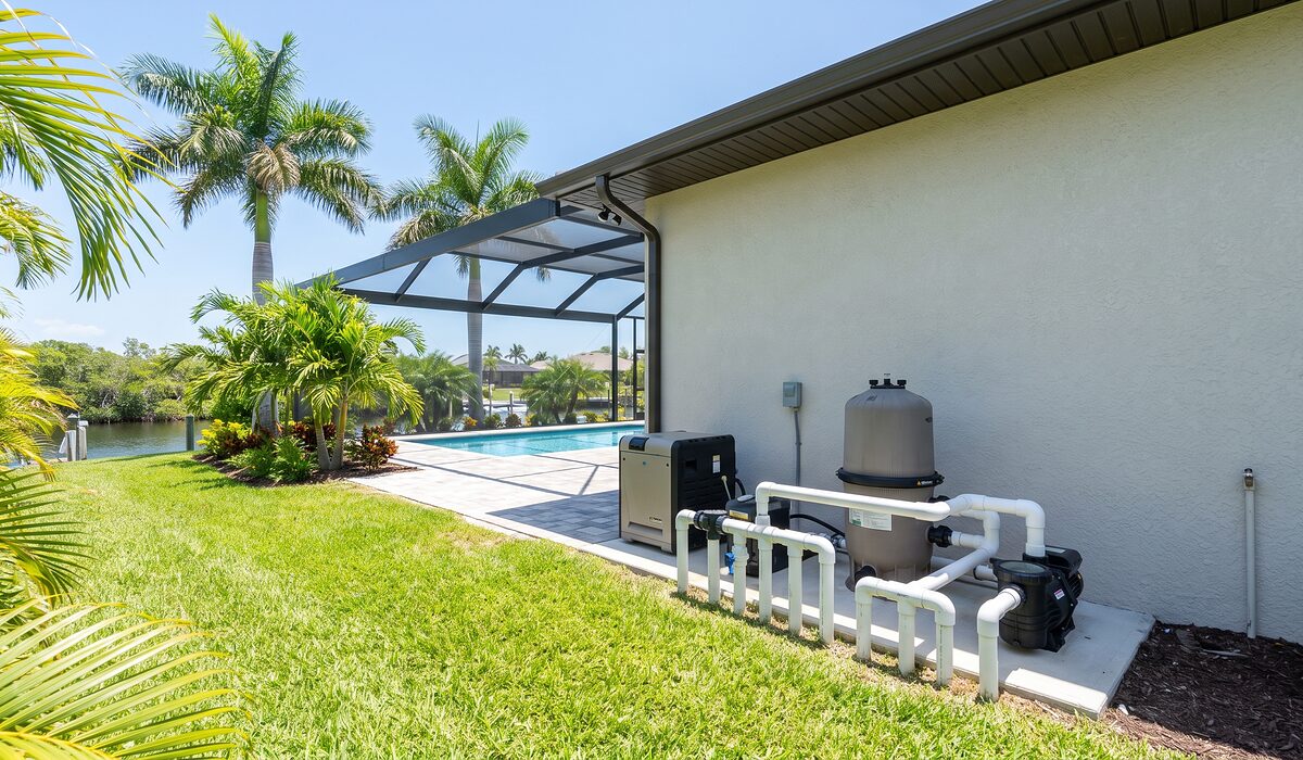 Pool equipment pad with pump, filter, and plumbing beside a Florida home