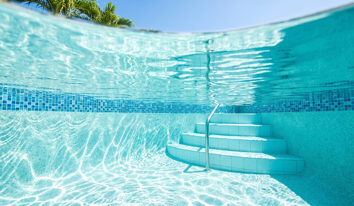 Underwater view of a clear swimming pool with sunlight through the water