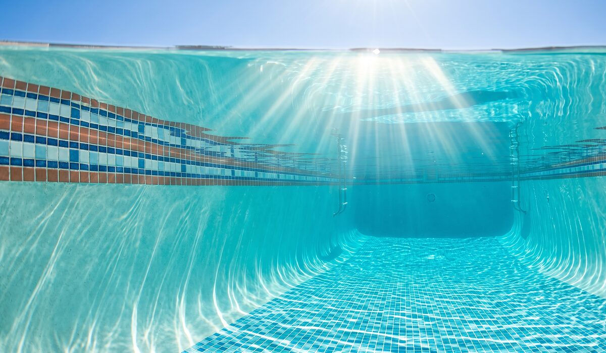 Underwater view of a clear swimming pool with sunlight through the water