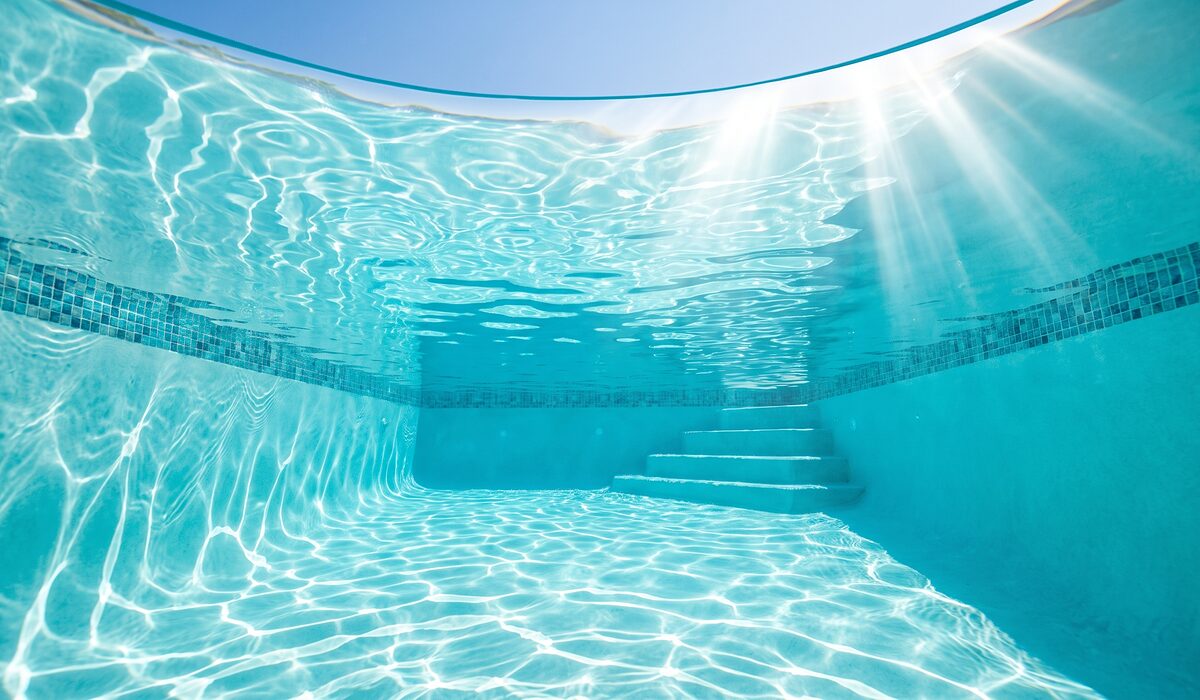 Underwater view of a clear swimming pool with sunlight through the water