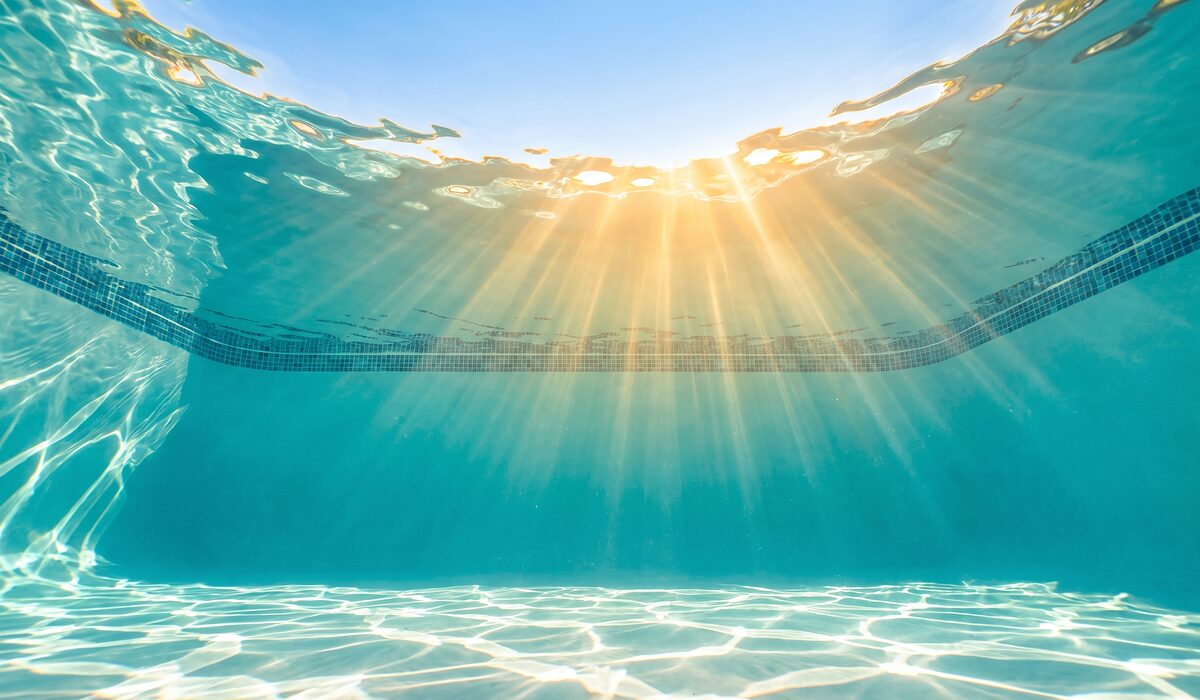 Underwater view of a clear swimming pool with sunlight through the water