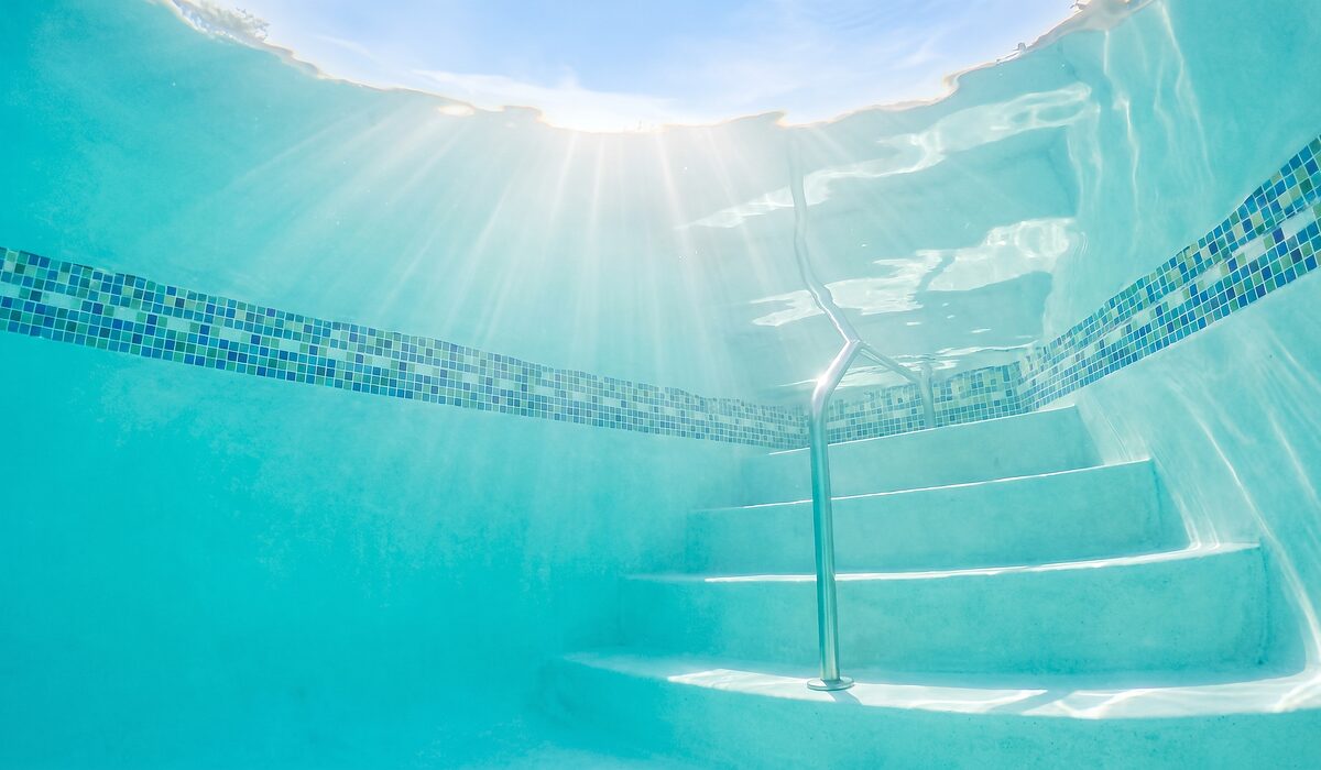 Underwater view of a clear swimming pool with sunlight through the water