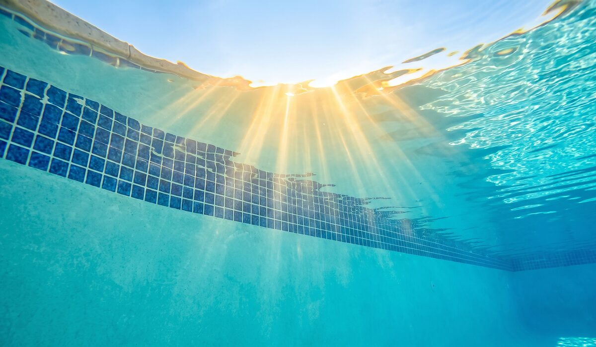 Underwater view of a clear swimming pool with sunlight through the water
