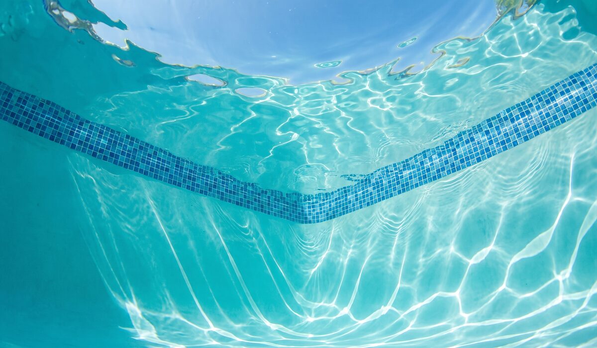 Underwater view of a clear swimming pool with sunlight through the water