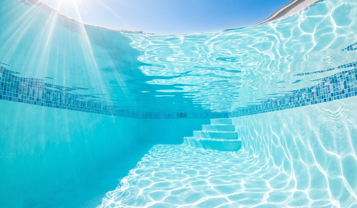 Underwater view of a clear swimming pool with sunlight through the water