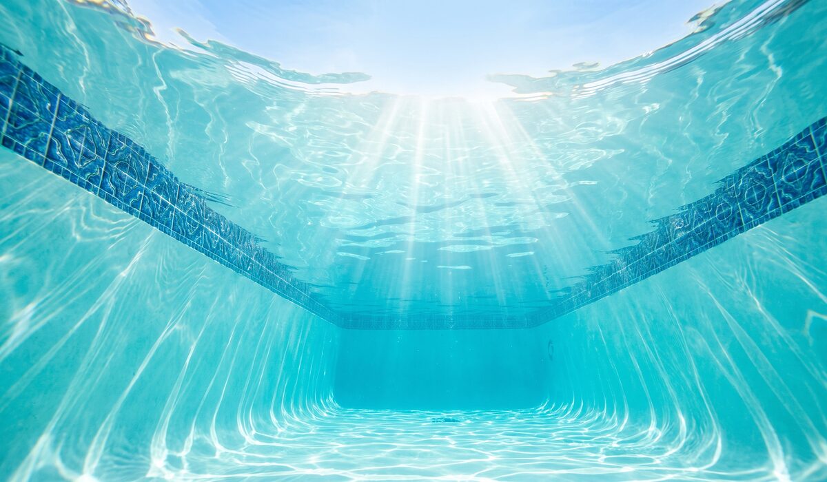 Underwater view of a clear swimming pool with sunlight through the water