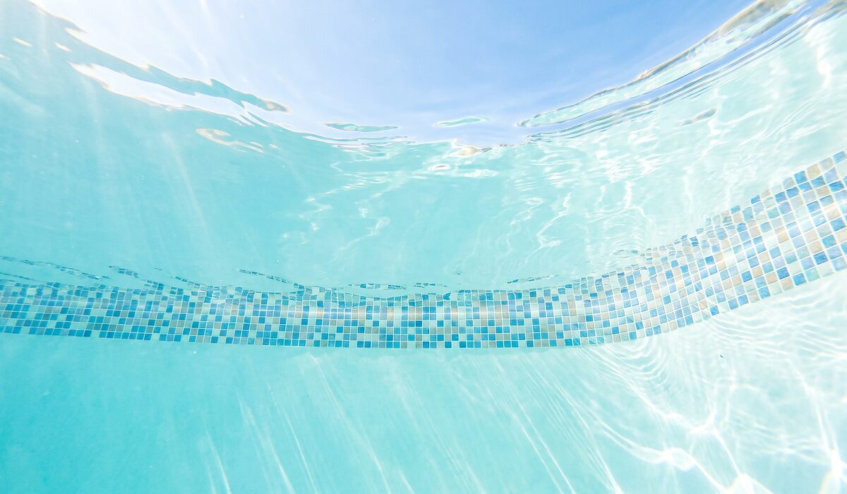 Underwater view of a clear swimming pool with sunlight through the water