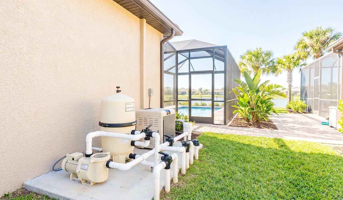 Pool equipment pad with pump, filter, and plumbing beside a Florida home