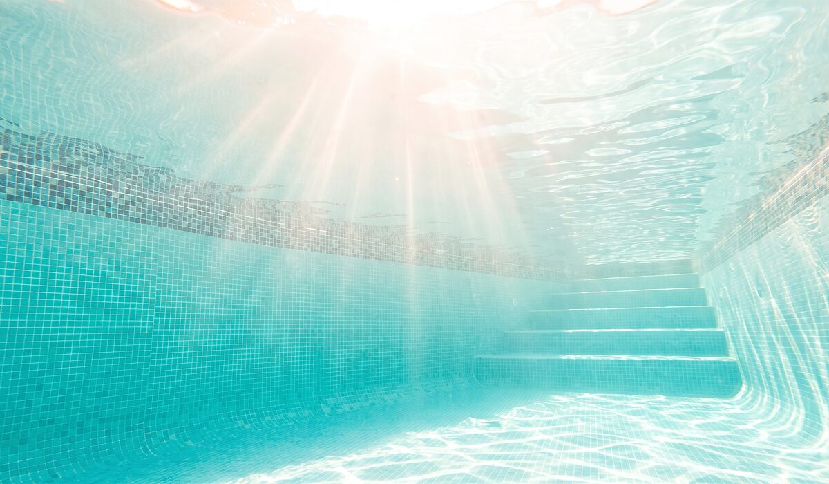 Underwater view of a clear swimming pool with sunlight through the water