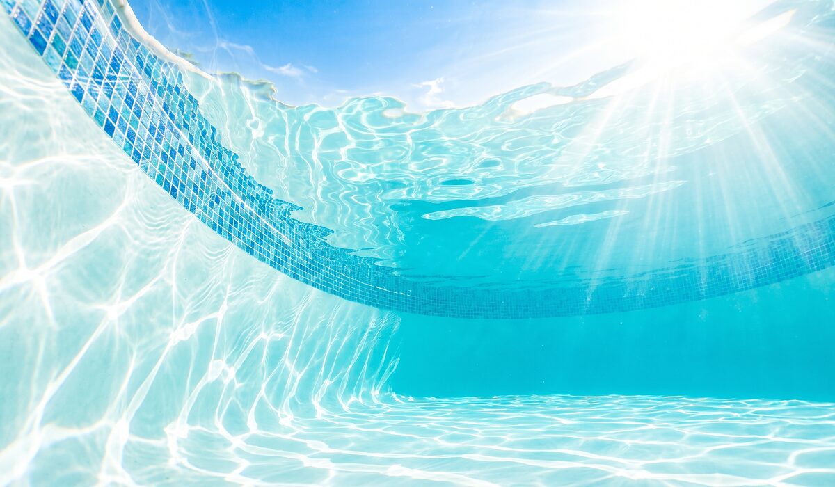 Underwater view of a clear swimming pool with sunlight through the water