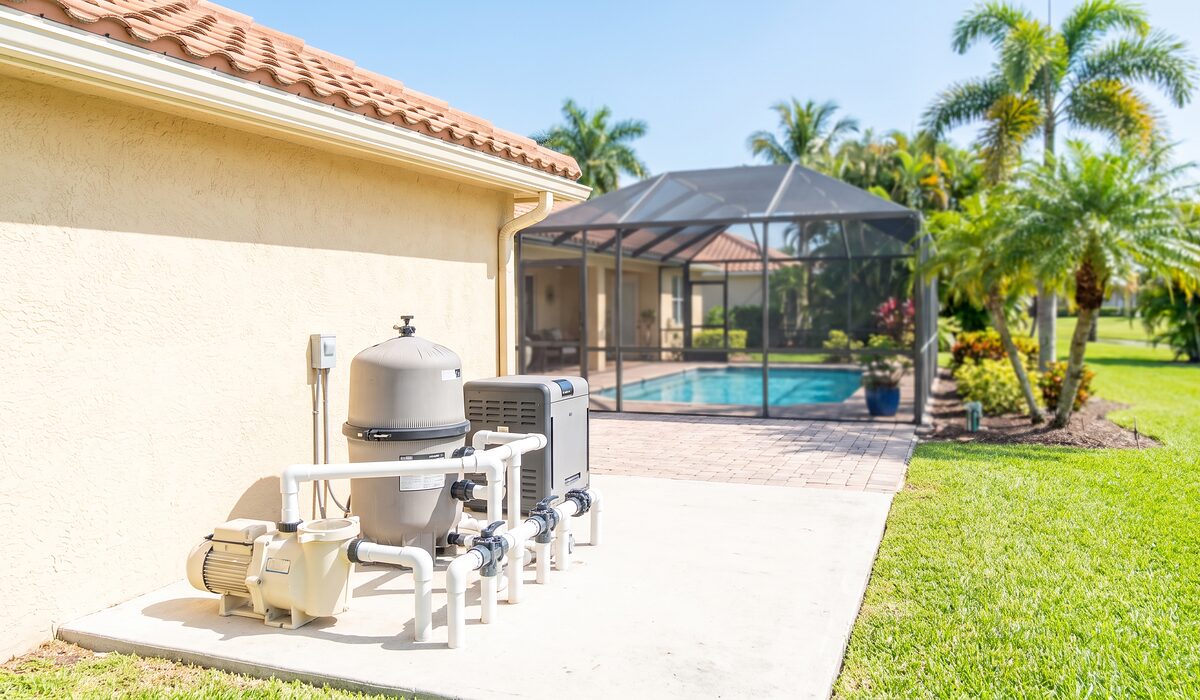 Pool equipment pad with pump, filter, and plumbing beside a Florida home