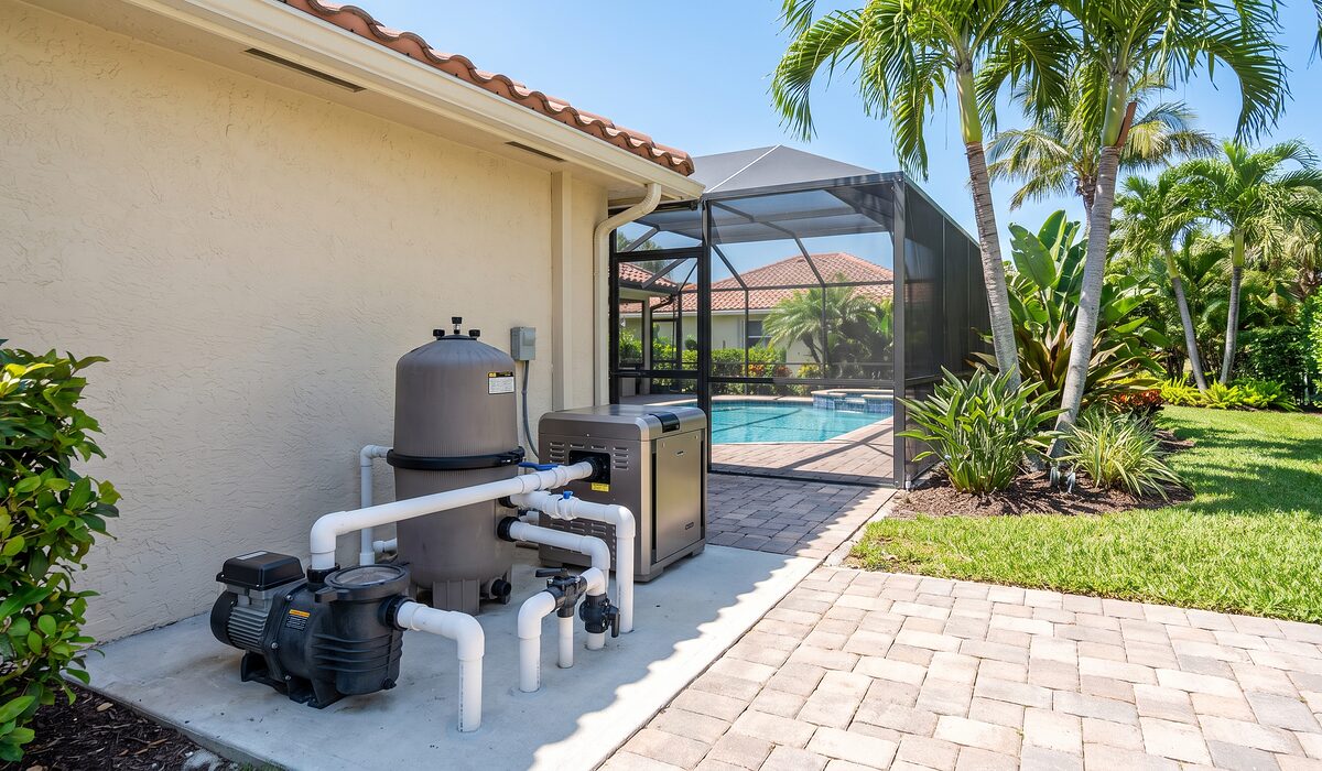 Pool equipment pad with pump, filter, and plumbing beside a Florida home