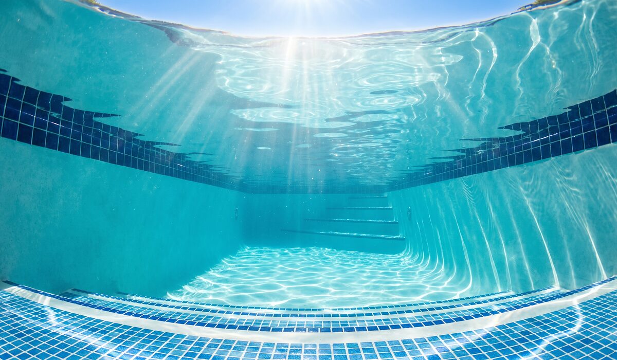 Underwater view of a clear swimming pool with sunlight through the water