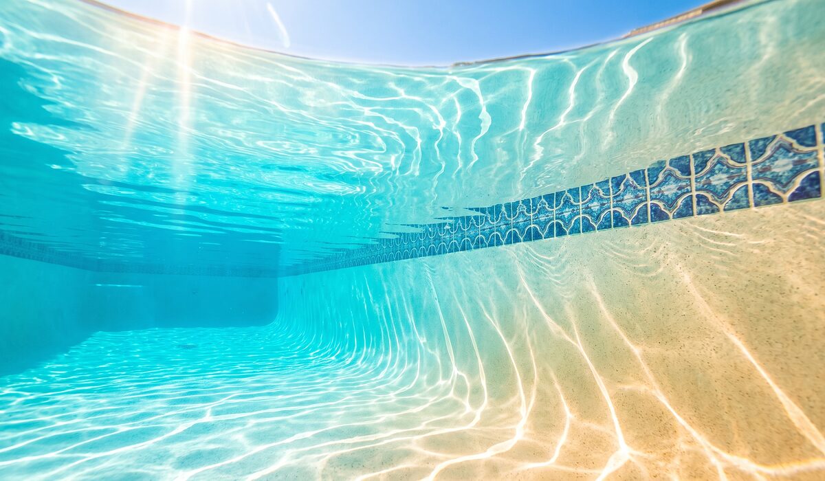 Underwater view of a clear swimming pool with sunlight through the water