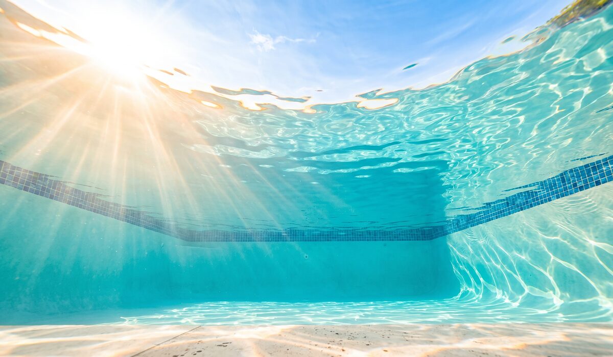 Underwater view of a clear swimming pool with sunlight through the water