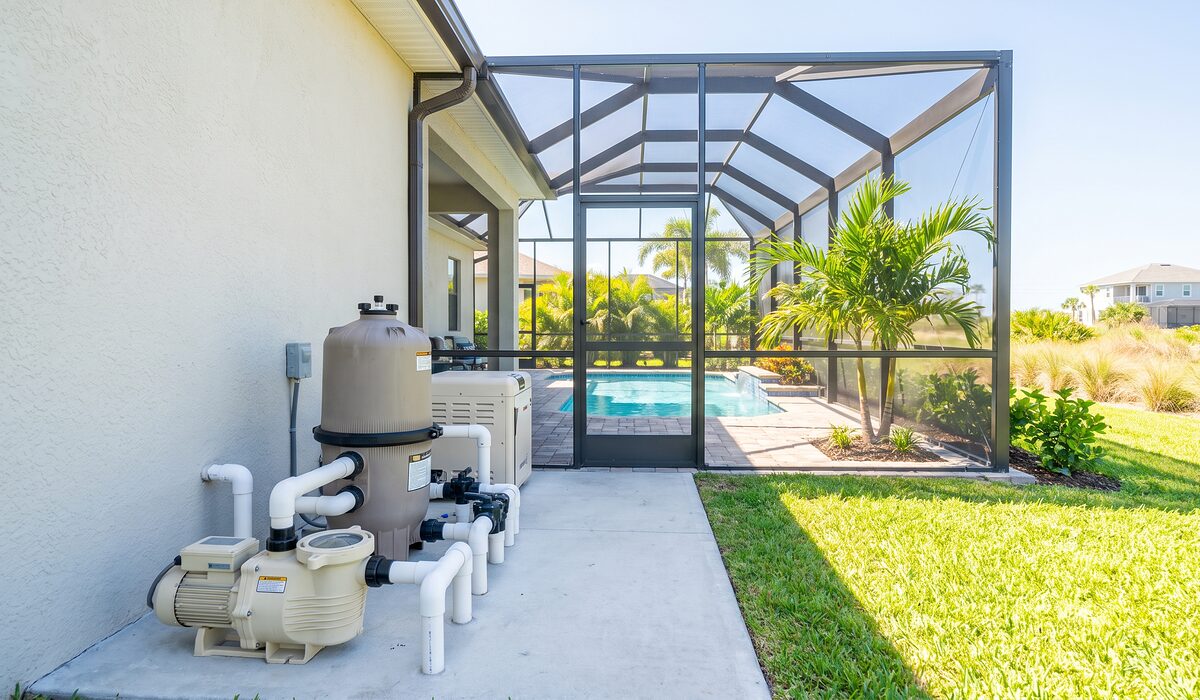 Pool equipment pad with pump, filter, and plumbing beside a Florida home