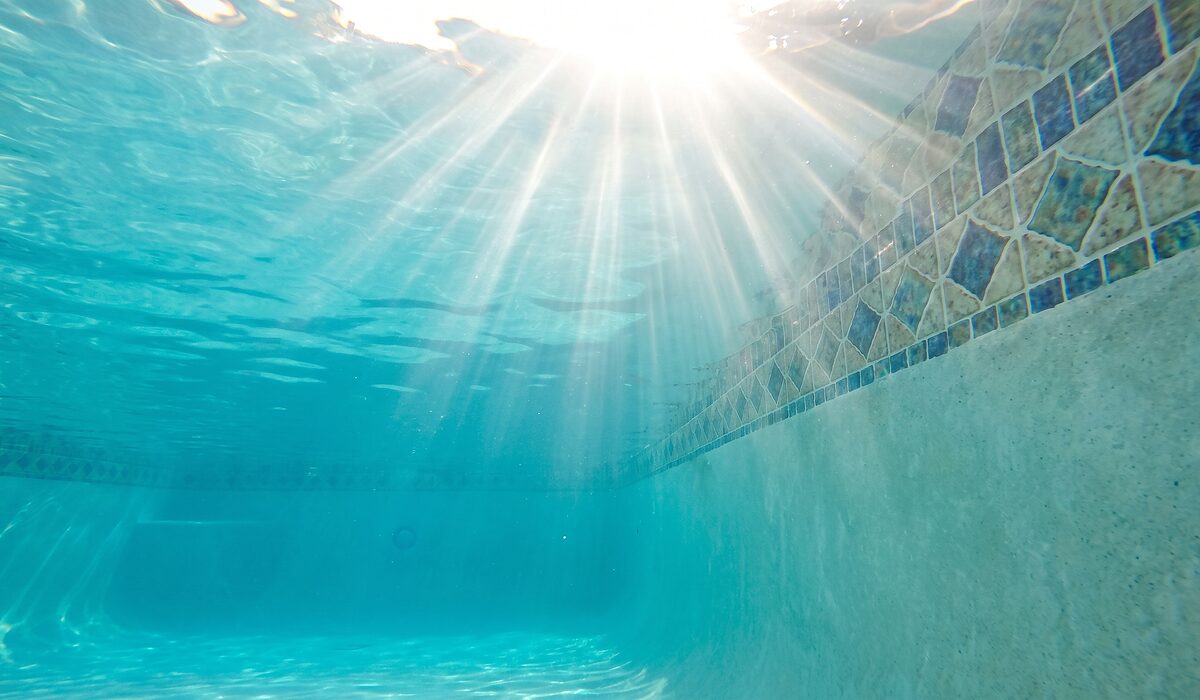 Underwater view of a clear swimming pool with sunlight through the water