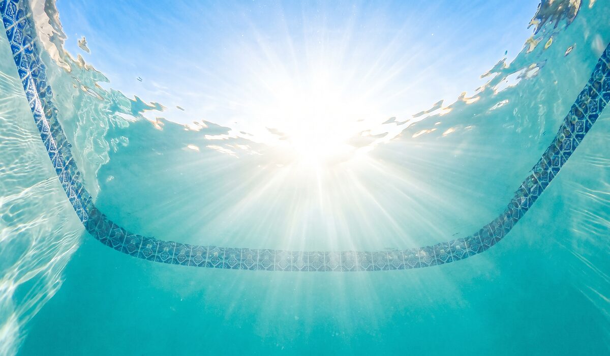 Underwater view of a clear swimming pool with sunlight through the water