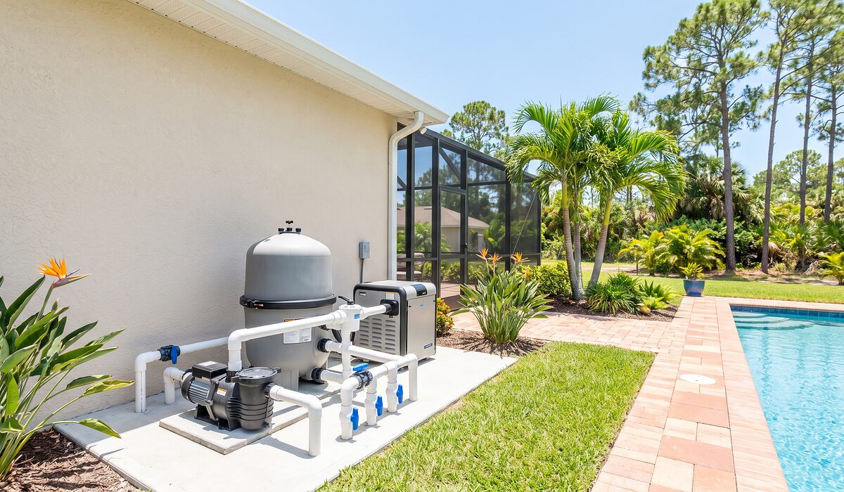 Pool equipment pad with pump, filter, and plumbing beside a Florida home
