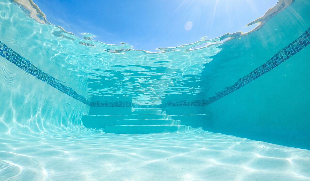 Underwater view of a clear swimming pool with sunlight through the water