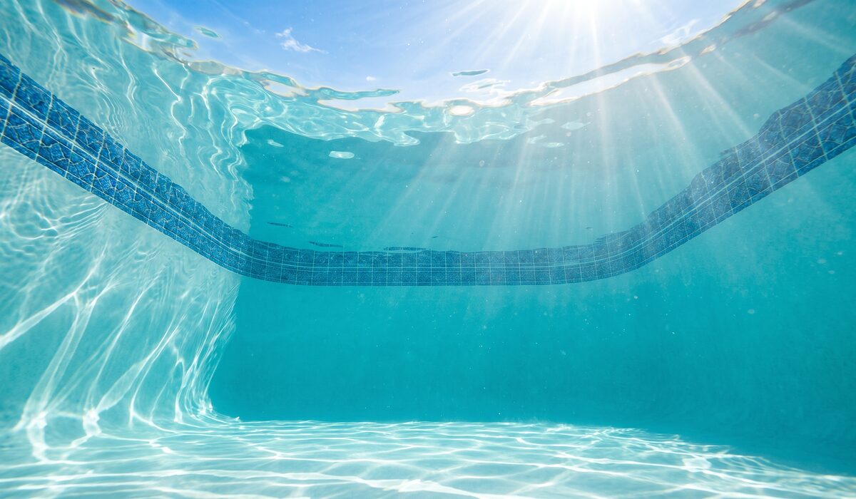 Underwater view of a clear swimming pool with sunlight through the water