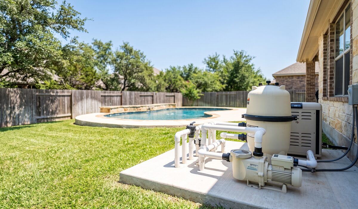 Pool equipment pad with pump, filter, and plumbing beside a Texas home