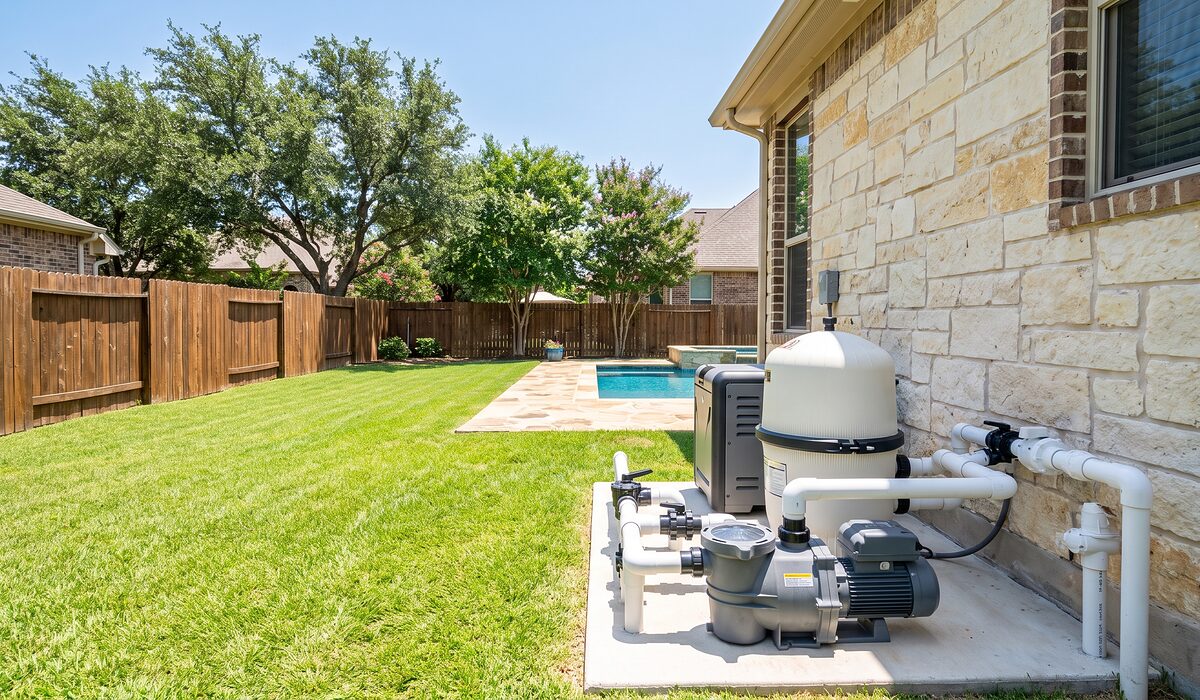 Pool equipment pad with pump, filter, and plumbing beside a Texas home