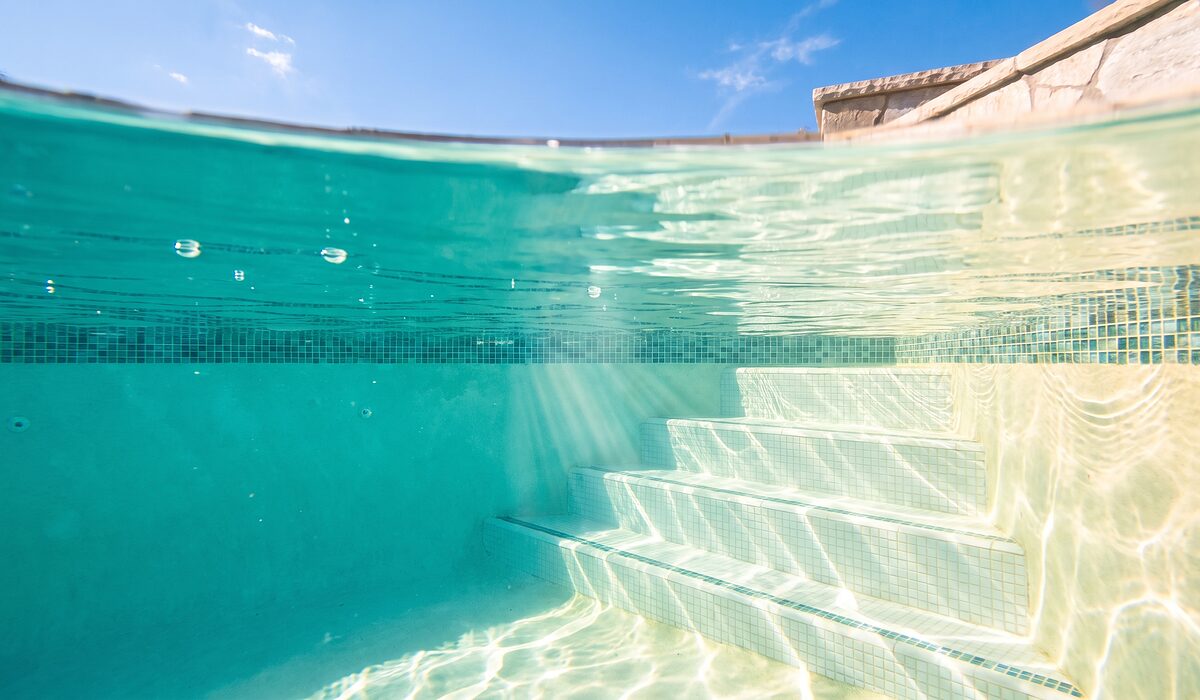 Underwater view of a clear swimming pool with sunlight through the water