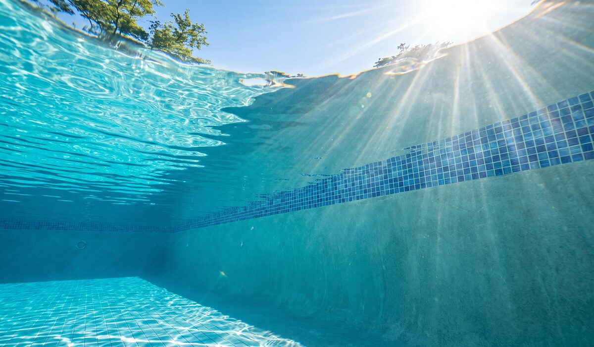 Underwater view of a clear swimming pool with sunlight through the water