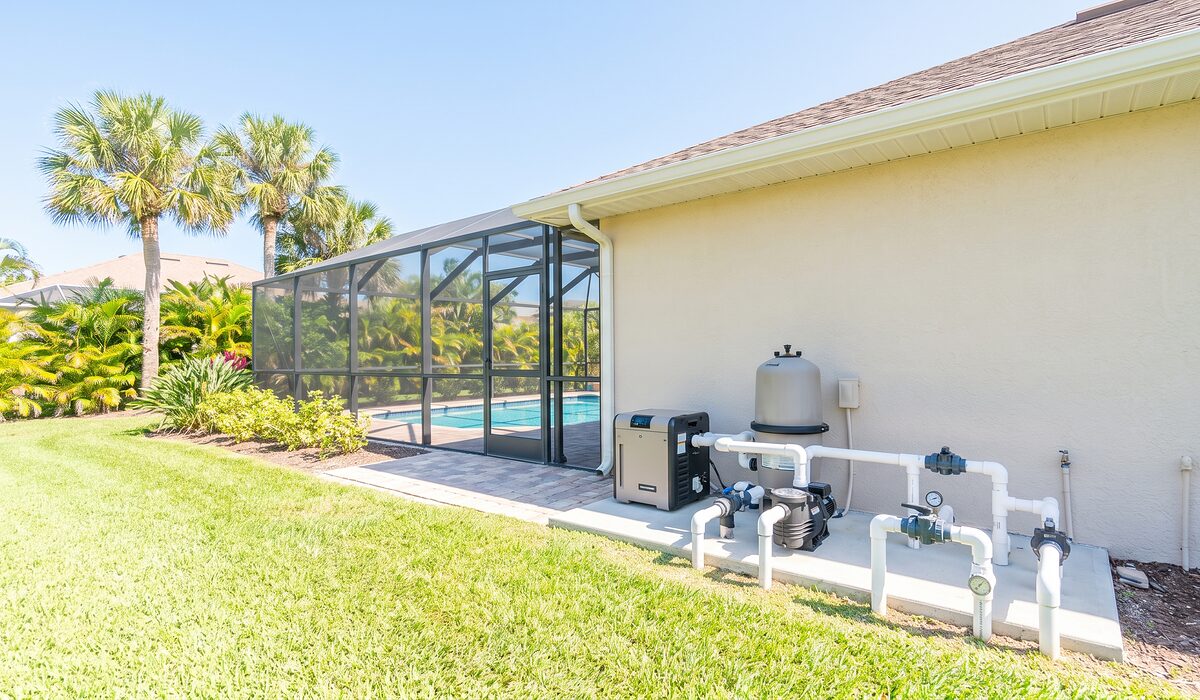 Pool equipment pad with pump, filter, and plumbing beside a Florida home